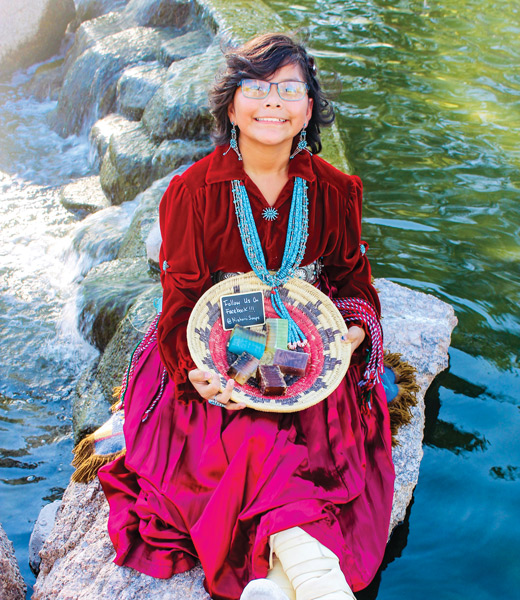 Kamia Begay holding a basket of the soaps she makes for her shop Nizhóní Soaps