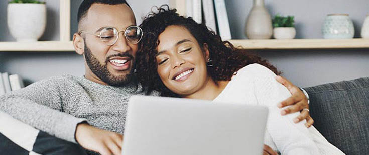 Couple using laptop couch online computer Couple using laptop couch online computer