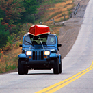 Jeep driving with canoe on roof