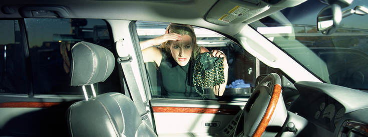 Woman looking into window of locked car with keys in ignition Woman looking into window of locked car with keys in ignition