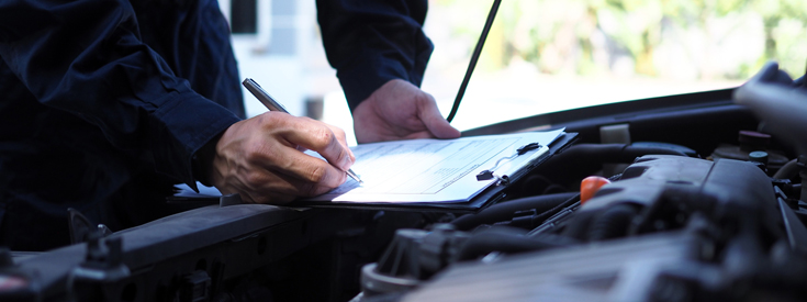 Mechanic with clipboard looking at car engine Mechanic with clipboard looking at car engine