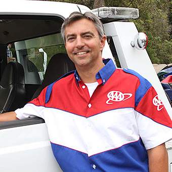 AAA tow truck driver posing by an assistance vehicle