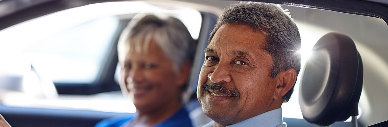 An older couple in a car, smiling at the camera