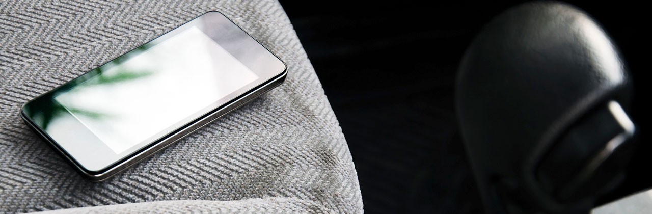 Smartphone sitting on a car seat next to the gearshift