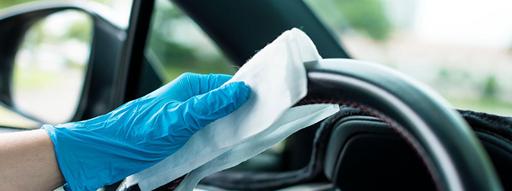 Cleaning steering wheel Hands with blue gloves and cleaning the car