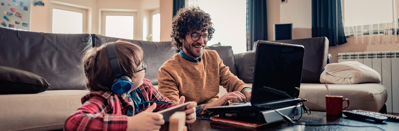 A father and son use mobile devices in their living room at home