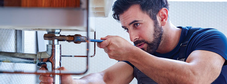 Male plumber adjusting sink pipe