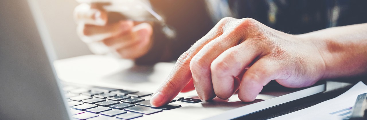 A person uses a laptop while holding a credit card