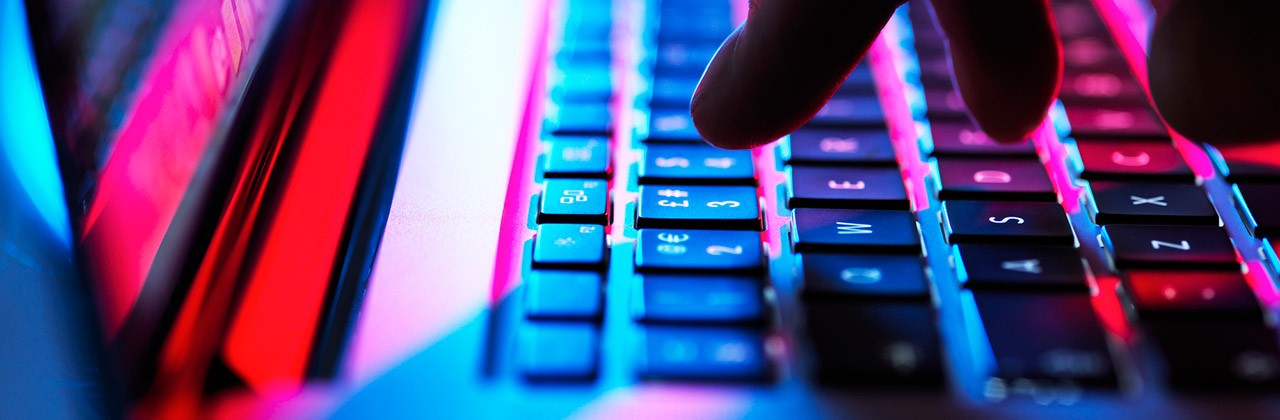 Fingers typing on a laptop keyboard in the dark