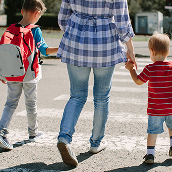 Parent crossing street in crosswalk with young children