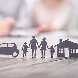 Paper cut-outs of a family flanked by a car and house
