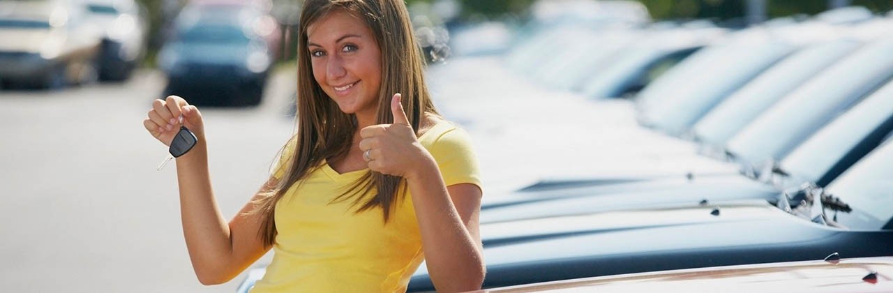 A Young Woman With Keys To A Vehicle In A Car Dealership
