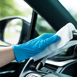 Hands with blue gloves and cleaning the car
