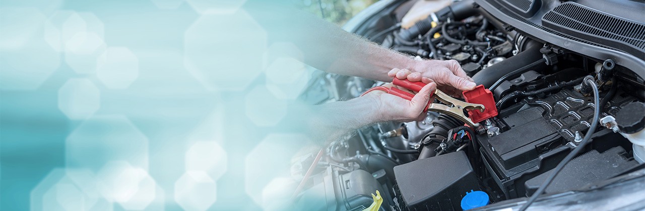 Hands of car mechanic using cables to start a car engine. panoramic banner