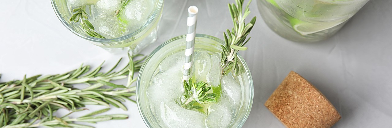 Flat lay composition with lime and rosemary cocktail on gray table