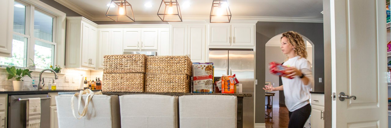 Kati Wadsworth working with pantry goods and baskets piled on a client's kitchen counter