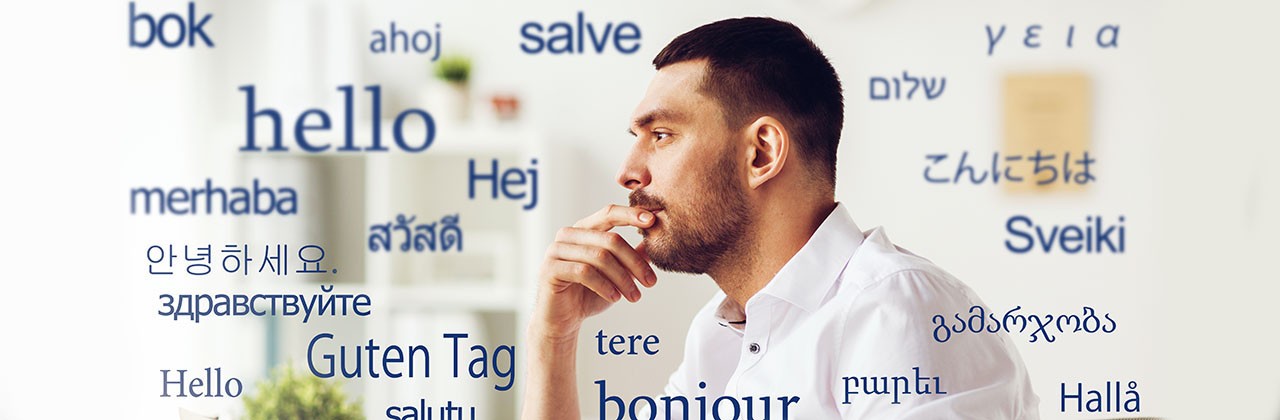 translation, business, and technology concept - male translator or businessman with laptop computer thinking at office over greeting words in different foreign languages