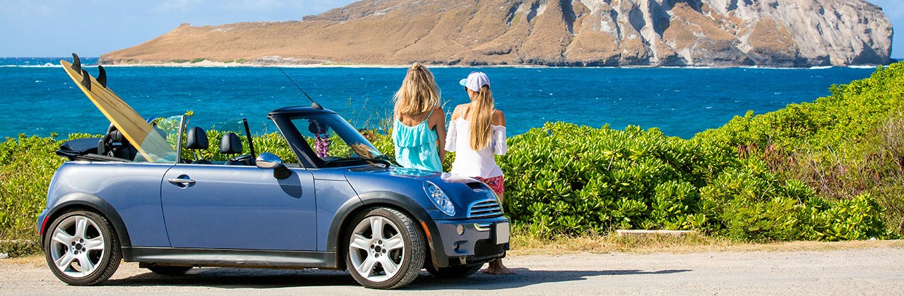 Friends laughing having fun in Oahu island, USA travel lifestyle. Hawaii surfers people lifestyle happy living friends talking on beach relaxing from surfing with surfboards.