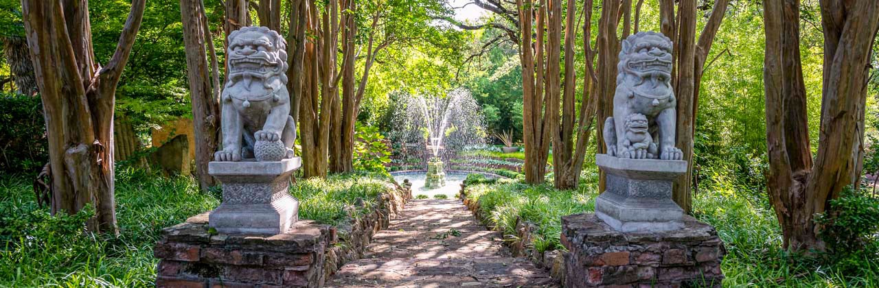 Chinese guardian lion statues flanking the pathway leading to a fountain in Chandor Gardens