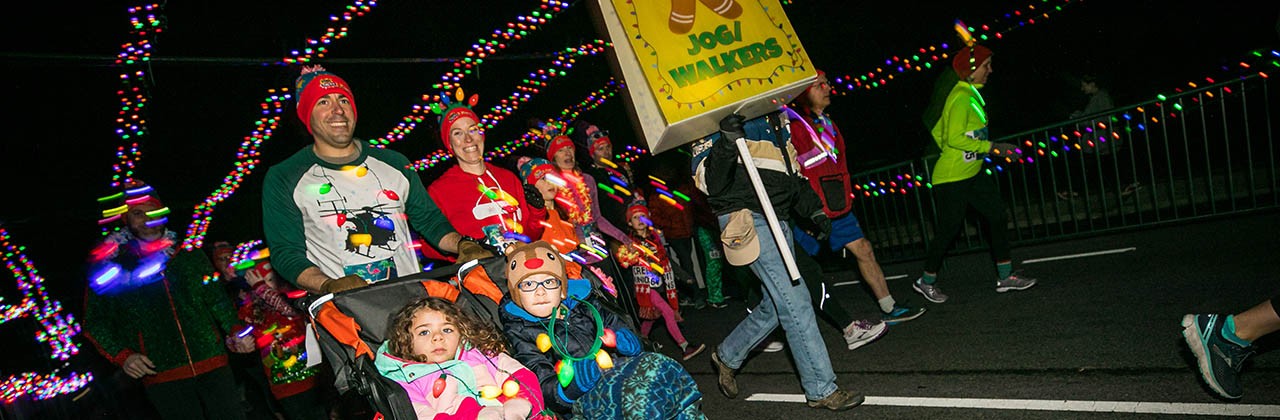 Man pushing a stroller with 2 children during the CarMax Tacky Lights Tour annual charity run