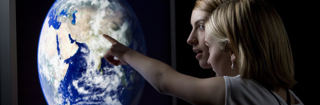 Woman and child looking at Earth on a computer screen