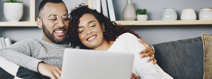Couple using laptop couch online computer Couple using laptop couch online computer