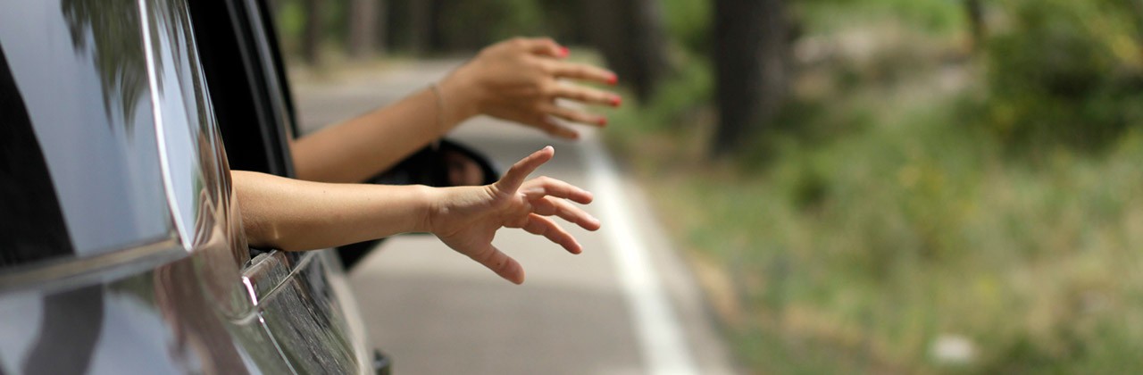 Passengers put their hands out of car windows while driving