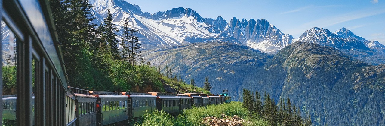 The White Pass & Yukon Route train climbs the White Pass railway with many passenger rail cars in tow.