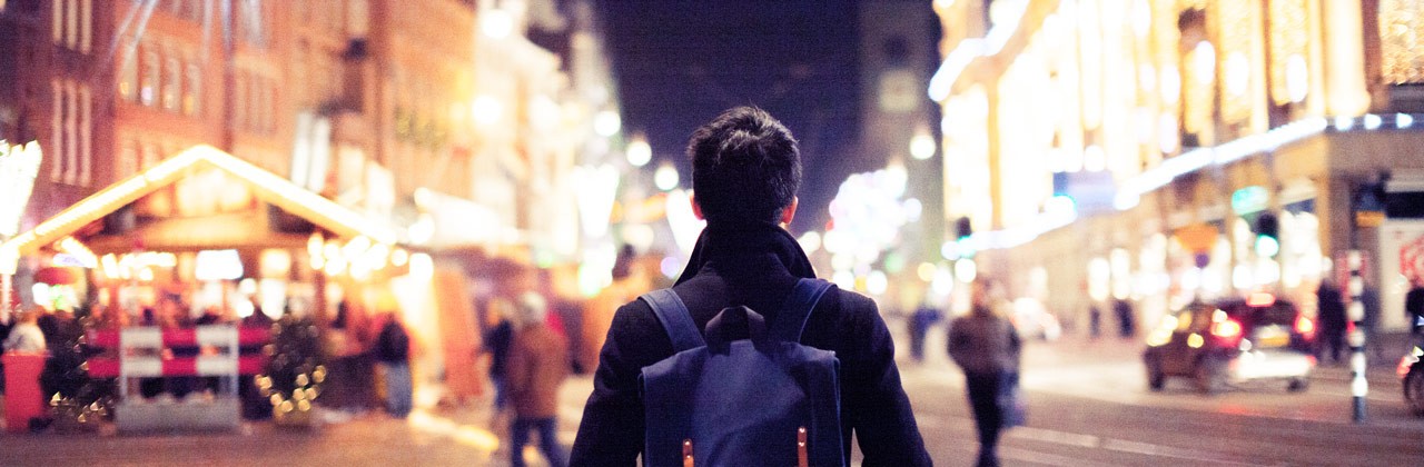 Man walking along well-lit street at night