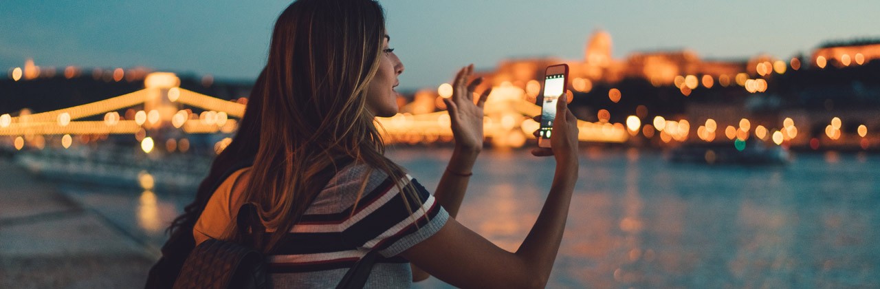 Woman using her phone to take a photo at night