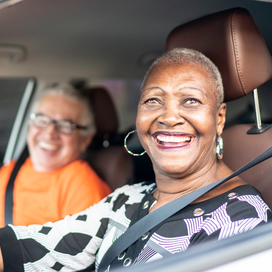 Portrait of senior woman driving a car and a friend on the passenger seat