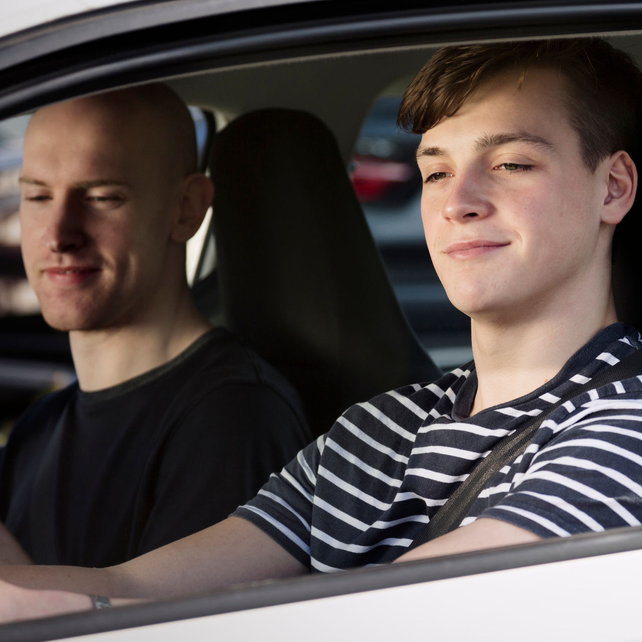 Male teenager in car with instructor.
