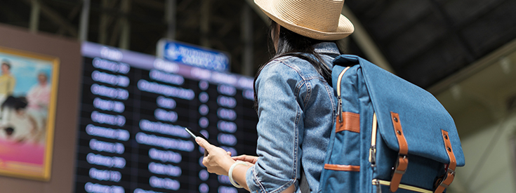 Woman looking at airport arrival and departure screen