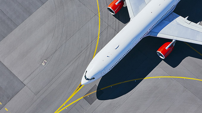 A plane taxiing on the tarmac at an airport, seen from above