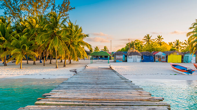 A beach with wooden shacks and a pier in the Dominican Republic