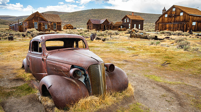 A rusted car and many wood buildings at Bodie State Park's ghost town