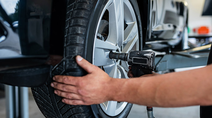 Mechanic removing a car wheel to rotate tires