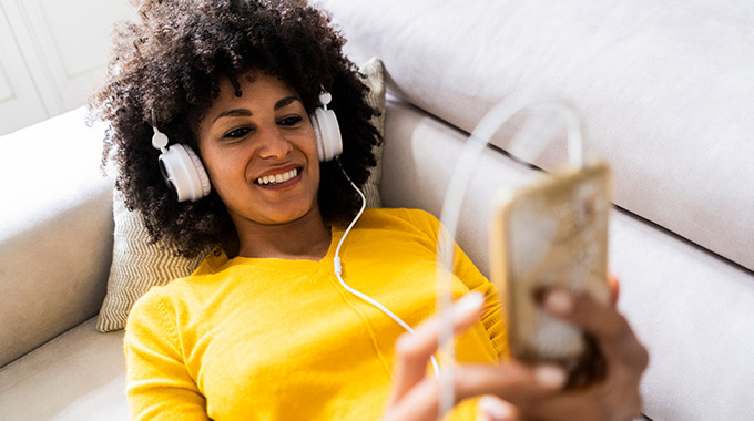 A woman uses a smartphone while wearing headphones 