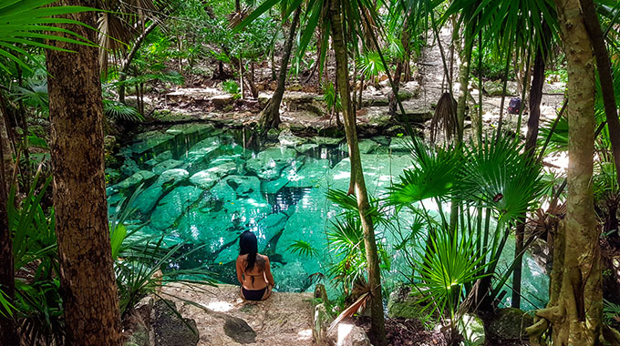 A woman sitting on the edge of Cenote Azul