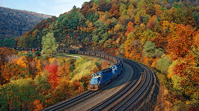 A freight train rounds the bend of Horseshoe Curve amid fall foliage.