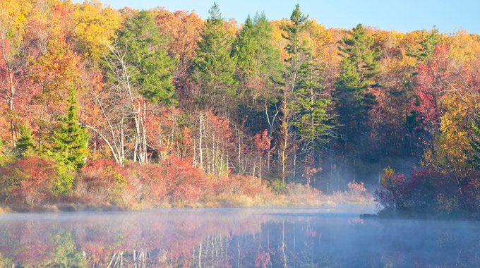 Mist over Pocono Mountain Lake in front of autumn trees