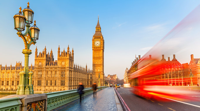 A bus zips by passersby in London, with Big Ben in the background