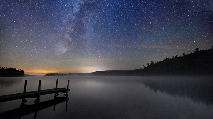 A dock on a lake under the Milky Way in the White Mountains of New Hampshire