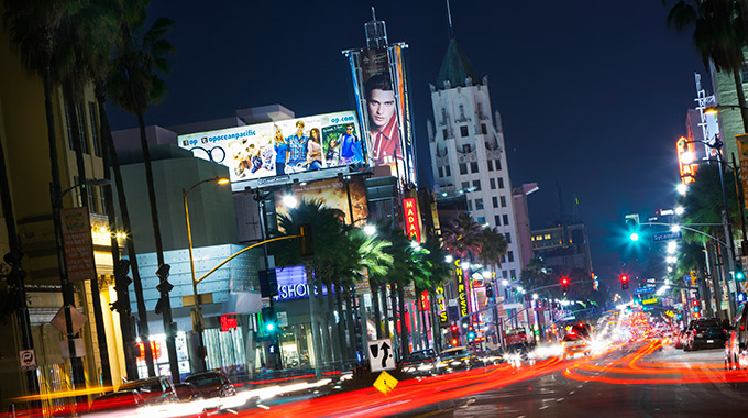 Hollywood Boulevard at night facing east, with lights from traffic and signs. 