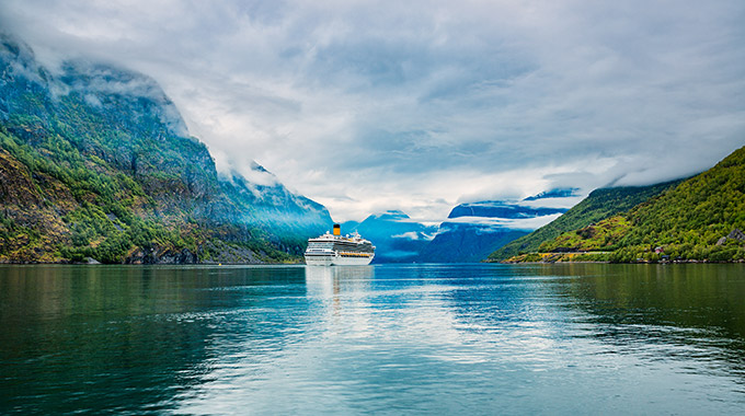 A cruise ship makes its way through a fjord in Norway