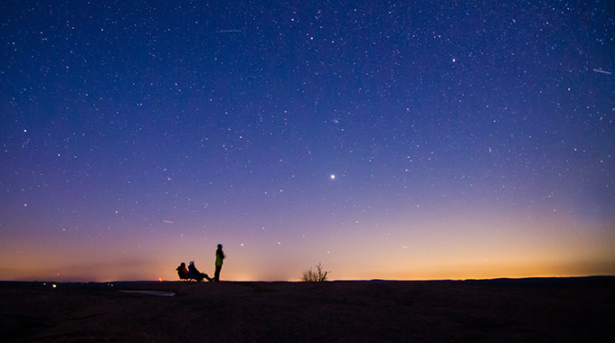 A night view of the sky above Enchanted Rock State Natural Area in Texas, with a couple stargazers