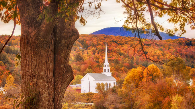 White chapel seen in the middle of fall trees in Stowe, Vermont