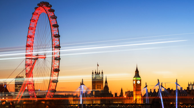 The London Eye lit up red at night across the Thames from Westminster