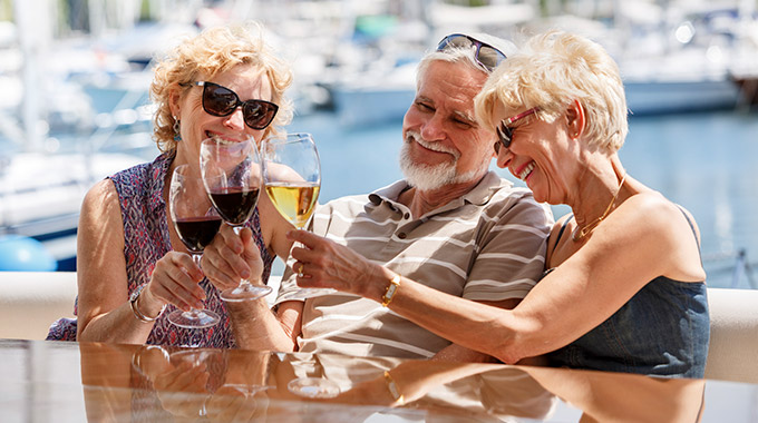 Three older travelers drinking wine together on a boat