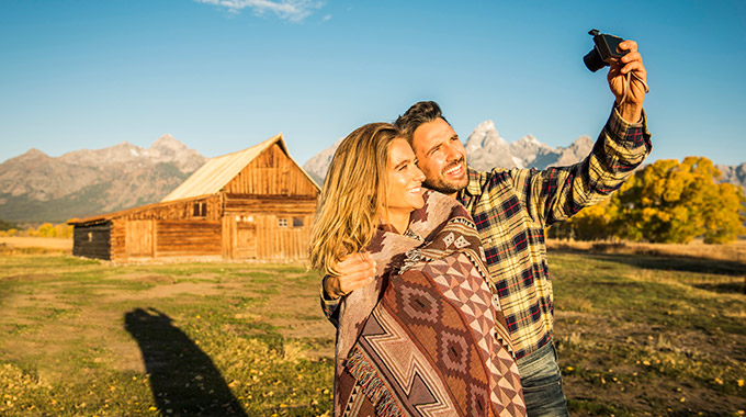 A couple takes a selfie with the Grand Tetons in the background near Jackson, Wyoming